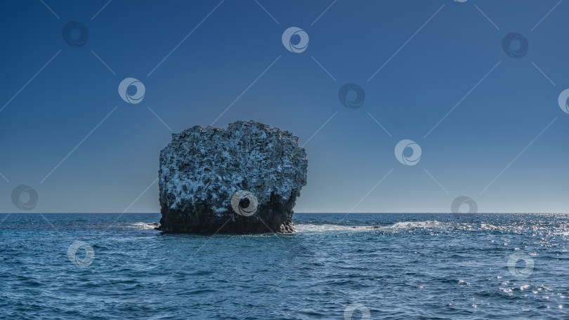 Скачать Одинокий маленький скалистый остров в синем океане. фотосток Ozero