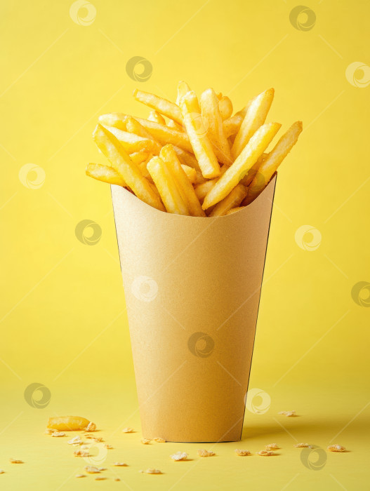Скачать Изысканная подача золотистого картофеля фри в высоком крафт-формочке на желтом фоне фотосток Ozero
