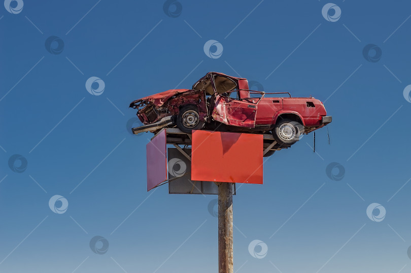 Скачать Разбитая красная машина на рекламном столбе на фоне голубого неба фотосток Ozero