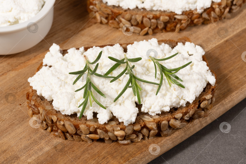 Скачать Вкусный ржаной хлеб со сливочным сыром и свежей зеленью на деревянной доске в деревенском стиле фотосток Ozero