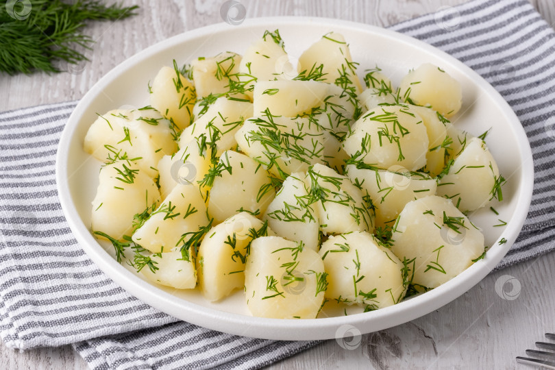 Скачать Свежеприготовленный картофель, украшенный укропом, на белой тарелке в уютной кухонной обстановке фотосток Ozero
