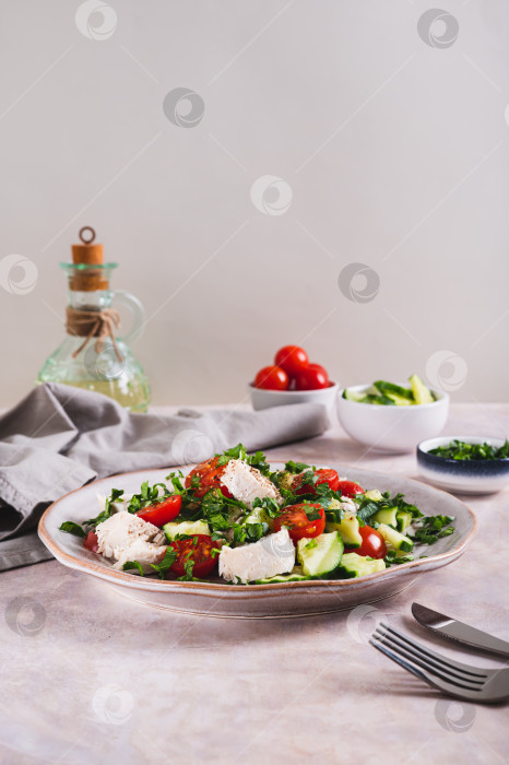 Скачать Домашний салат с огурцами, помидорами, курицей и зеленью на тарелке на столе в вертикальном положении фотосток Ozero