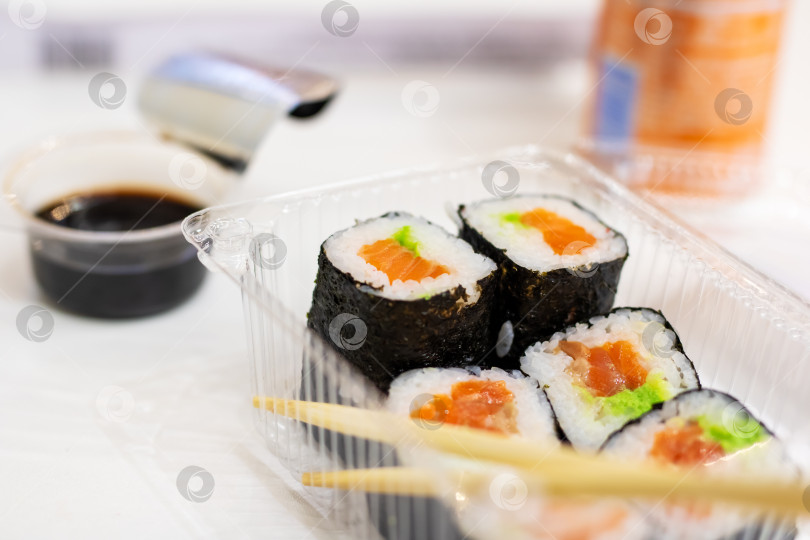 Скачать Пластиковый контейнер, наполненный вкусными суши и палочками для еды фотосток Ozero