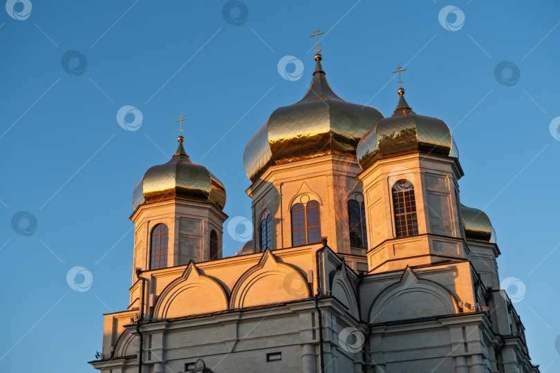 Скачать Золотые купола русской церкви ярко сияют на фоне ясного голубого неба во время заката в самом центре города - Ставрополе, Россия, 31 мая 2025 года фотосток Ozero