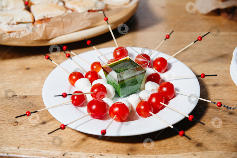 Скачать Шашлыки из капрезе с соусом Песто выложить на тарелку.  фотосток Ozero