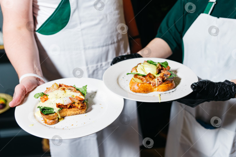 Скачать Шеф-повара готовят изысканные тосты с яйцом и беконом. фотосток Ozero