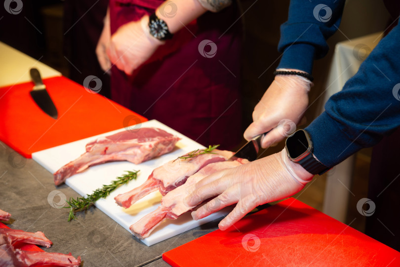 Скачать Шеф-повар нарезает сырые бараньи отбивные с розмарином.  фотосток Ozero