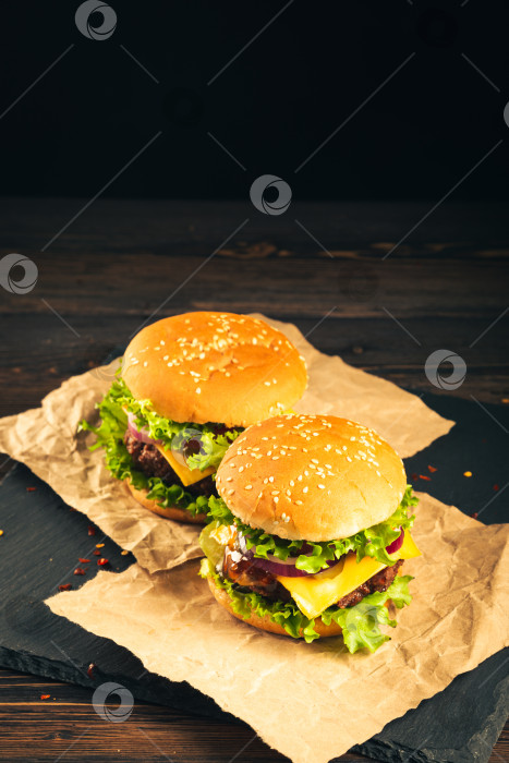 Скачать Вкусные гамбургеры на деревянной доске на темном фоне. фотосток Ozero