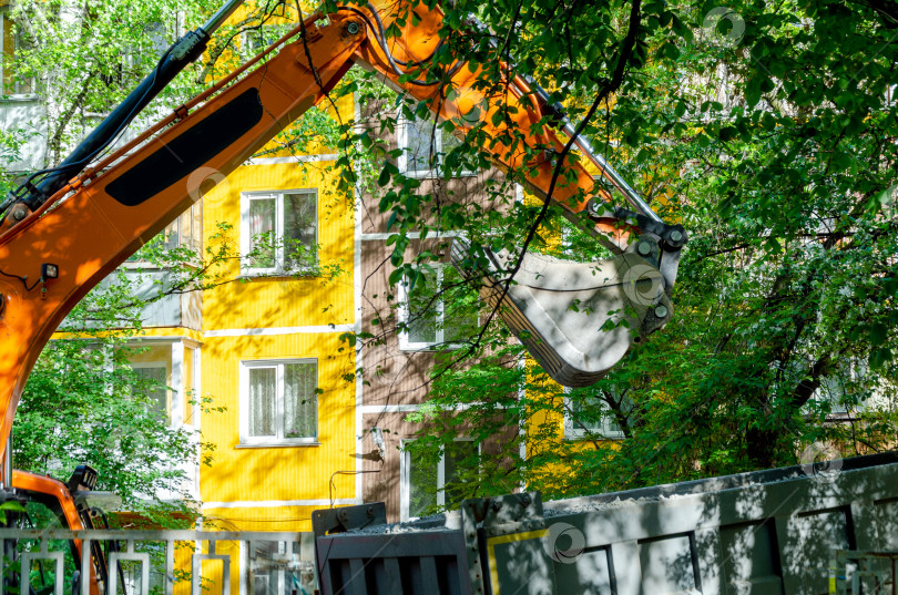 Скачать Экскаватор загружает мусор в самосвал на городской улице фотосток Ozero
