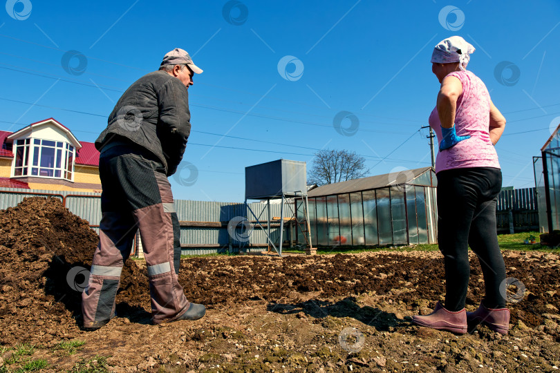 Скачать Мужчина и женщина занимаются садоводством, мужчина разбрасывает удобрения по пахотной земле. Естественная фотография. фотосток Ozero