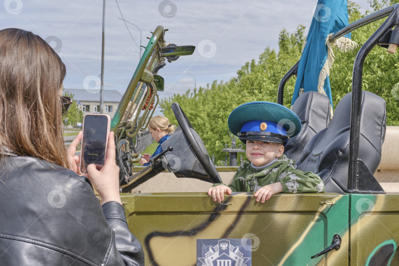 Скачать Ребенок в военном костюме позирует в армейской машине во время празднования Дня пограничника в России фотосток Ozero