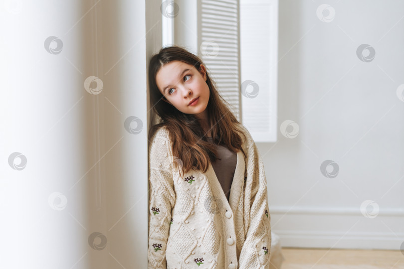 Скачать Портрет красивой девочки-подростка с длинными темными волосами у окна в белой студии фотосток Ozero