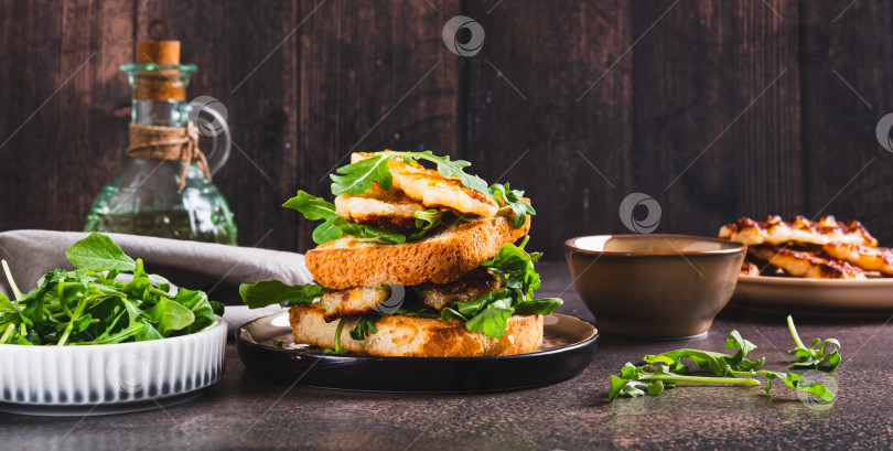 Скачать Вкусный сэндвич с жареным халлуми и рукколой на тарелке на веб-баннере table фотосток Ozero
