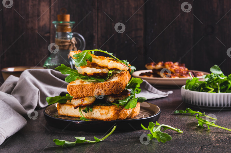 Скачать Вкусный бутерброд с жареным халлуми и рукколой на тарелке на столе фотосток Ozero