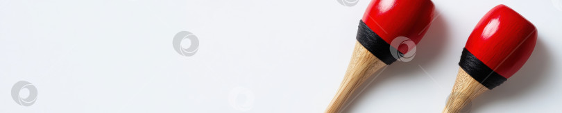 Скачать Ярко-красные маракасы на белом фоне. Концепция музыкального инструмента для праздничных торжеств и оформления фотосток Ozero