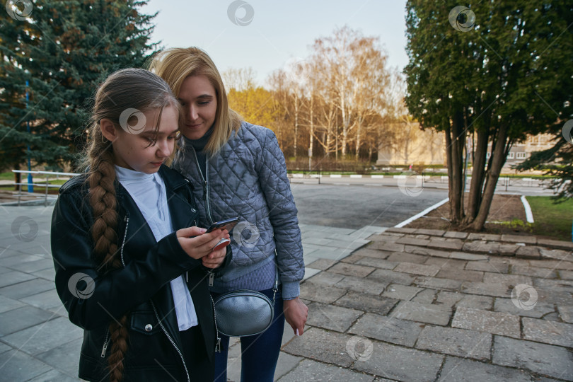 Скачать Дочь показывает что-то забавное, и мать улыбается. Общественное место, парк. фотосток Ozero