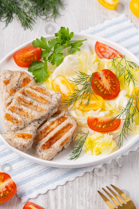 Скачать Полезный кето-ланч с куриным мясом на гриле и экологически чистыми помидорами и зеленью. Запеченная куриная грудка, филе и салат из свежих овощей на белом деревянном столе, copy space фотосток Ozero