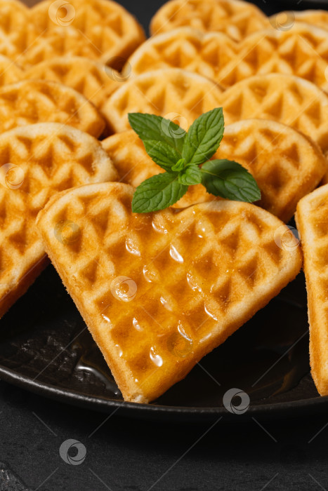 Скачать Вкусные вафли в форме сердца с сиропом и мятой на черной тарелке, идеально подходящие для завтрака или десерта фотосток Ozero