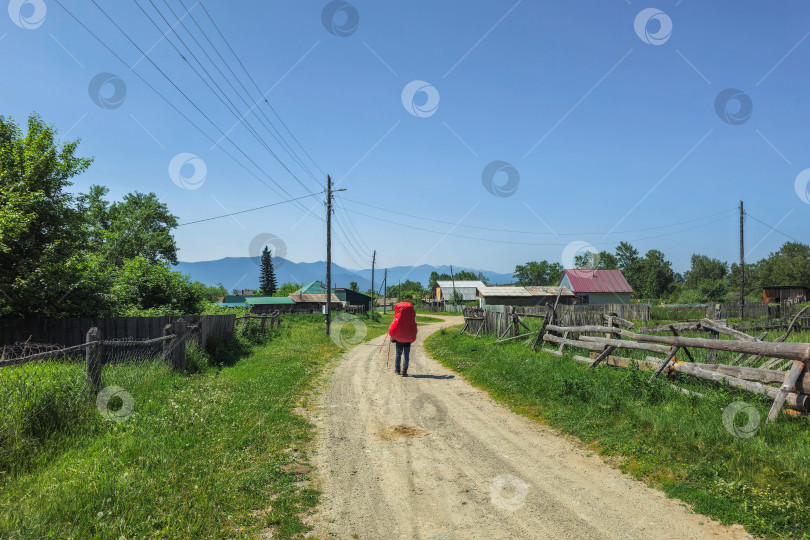 Скачать Путь через отдаленную деревню, турист с рюкзаком фотосток Ozero