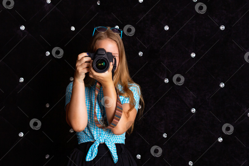 Скачать Девушка фотографирует зеркальным фотоаппаратом в студии на черном фоне фотосток Ozero