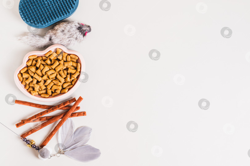Скачать Миска с кошачьим кормом, лакомство, щетка и игрушки на светлом фоне, вид сверху, пространство для копирования фотосток Ozero