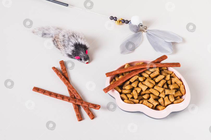 Скачать Миска с кошачьим кормом, лакомство, щетка и игрушки на светлом фоне фотосток Ozero