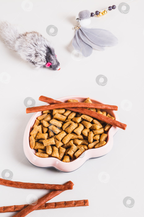 Скачать Миска с кошачьим кормом, лакомствами и игрушками на столе в вертикальном положении фотосток Ozero
