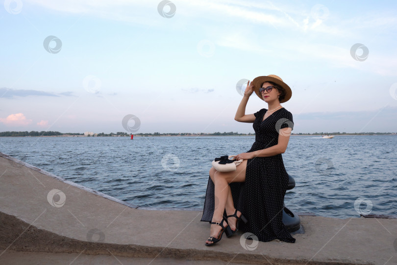 Скачать Женщина в платье в горошек позирует на набережной. фотосток Ozero