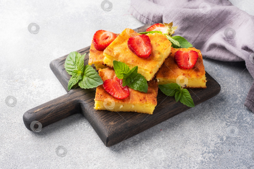 Скачать Творожная запеканка с клубникой и мятой. Вкусный домашний десерт из творога и свежих ягод со сливками. Серый бетонный фон, копия пространства. фотосток Ozero