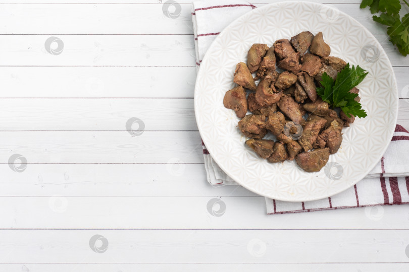 Скачать Жареная или запеченная куриная печень с луком и соусом, зеленью петрушки на тарелке. Мясное блюдо, обогащенное железом. скопировать с места фотосток Ozero