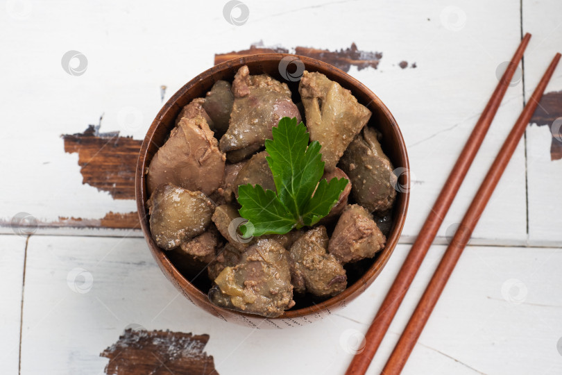 Скачать Обжаренная или запеченная куриная печень с луком и соусом, зеленью петрушки на тарелке. Мясное блюдо, обогащенное железом. фотосток Ozero