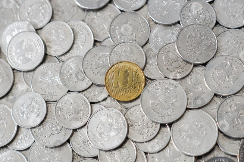 Скачать Золотая монета десять рублей в центре множества светлых разных монет фотосток Ozero