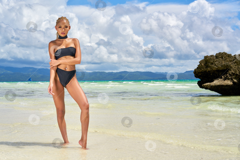 Скачать Женщина в черном купальнике стоит на фоне моря. фотосток Ozero