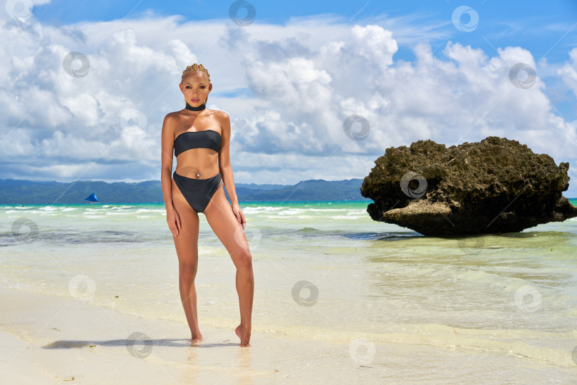 Скачать Женщина в черном купальнике стоит на фоне моря. фотосток Ozero