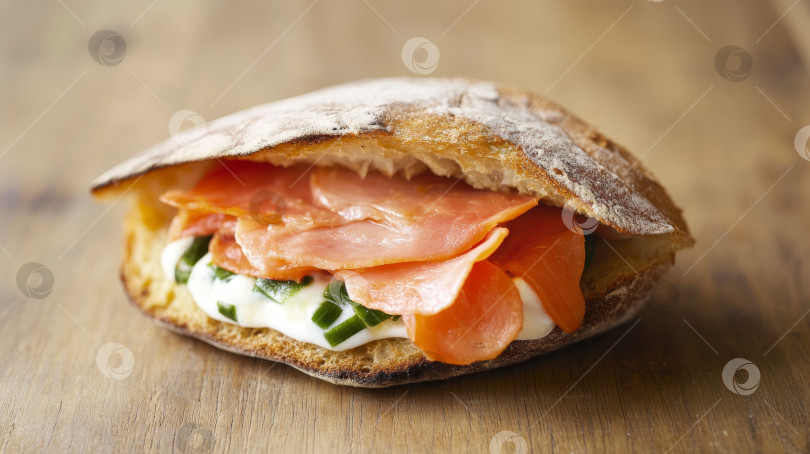 Скачать Пикантный сэндвич с копченым лососем и свежими овощами подается на деревянном столе в деревенском стиле в светлой кухонной обстановке фотосток Ozero