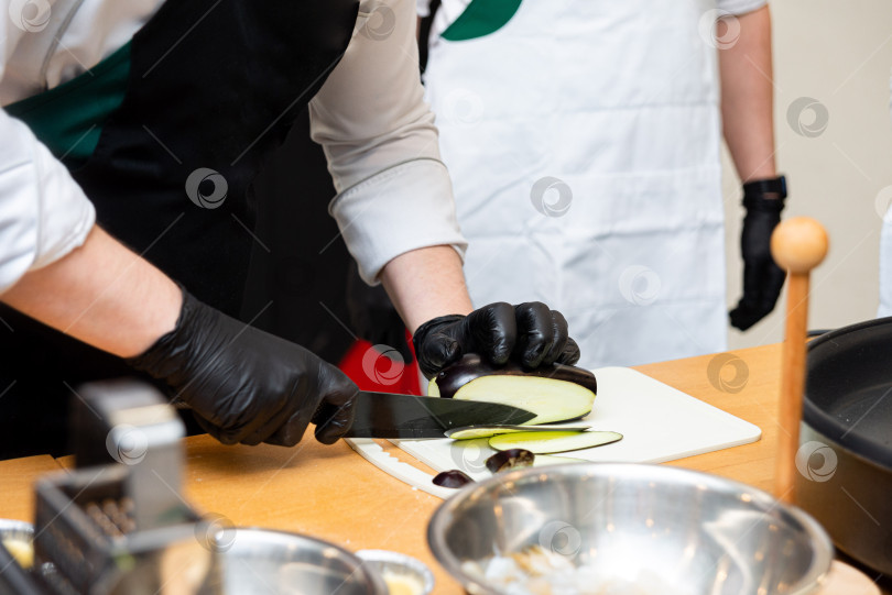 Скачать Шеф-повар нарезает баклажаны на профессиональной кухне.  фотосток Ozero