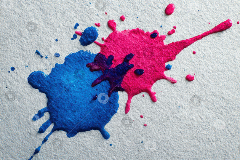 Скачать Яркие брызги голубой и розовой краски на текстурированной белой бумаге создают художественный фон, демонстрирующий красоту сочетания цветов и творческого самовыражения в динамичной визуальной композиции фотосток Ozero