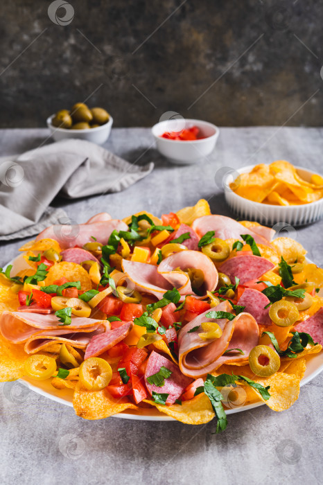 Скачать Мясные начос с чипсами, салями, сыром и оливками на тарелке на столе, вид сверху фотосток Ozero