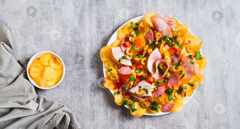Скачать Трендовые закуски - начос из мясной нарезки с картофельными чипсами на тарелке на столешнице посмотреть веб-баннер фотосток Ozero