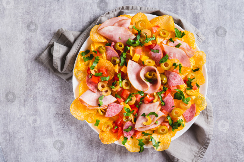 Скачать Крупный план мясных начос с чипсами, салями, сыром и оливками на тарелке, вид сверху фотосток Ozero