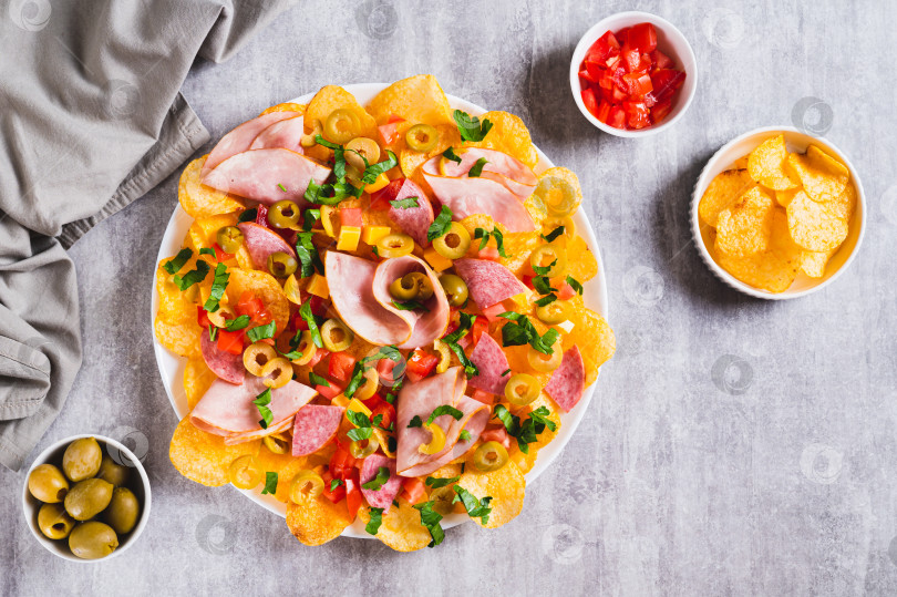Скачать Мясные начос с чипсами, салями, сыром и оливками на тарелке на столе, вид сверху фотосток Ozero