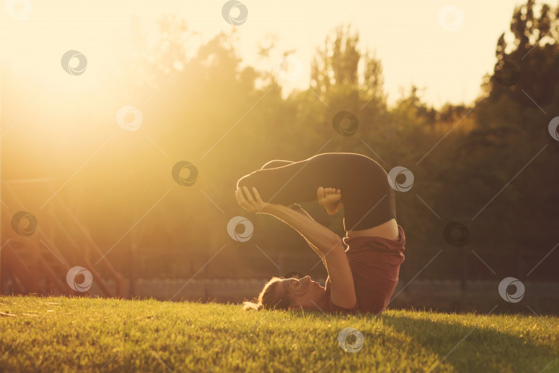Скачать Девушка занимается йогой в парке на закате фотосток Ozero