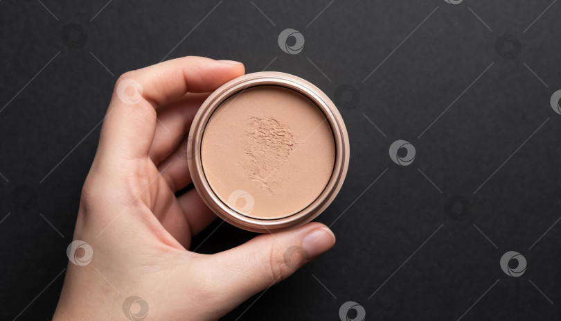 Скачать Косметическая бежевая пудра в женской ладони на черном фоне фотосток Ozero