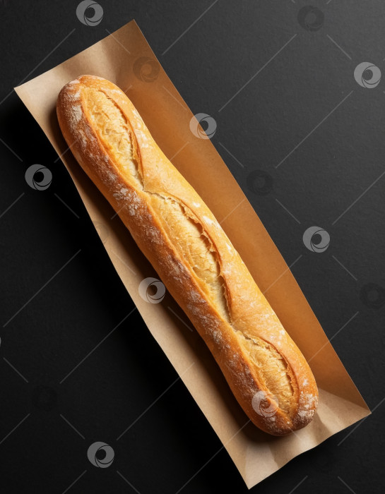 Скачать Хрустящий багет в крафтовой упаковке на черном фоне фотосток Ozero
