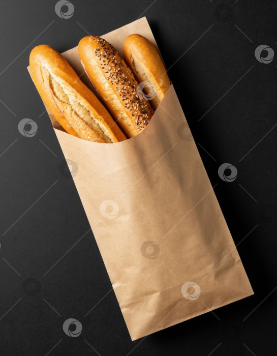 Скачать Хрустящий багет в крафтовой упаковке на черном фоне фотосток Ozero