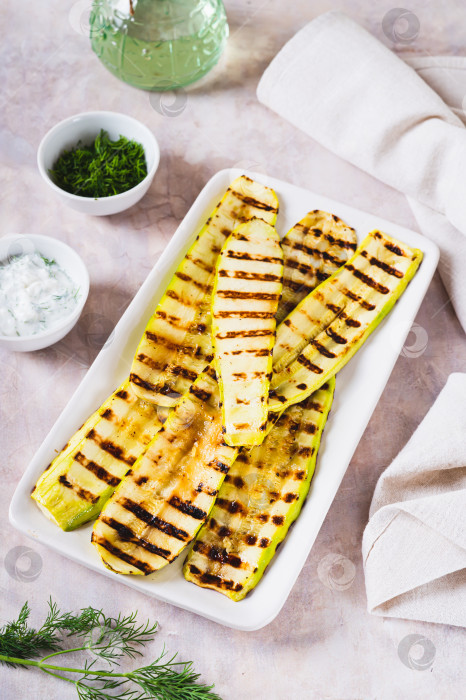 Скачать Вкусные овощи-гриль из кабачков на тарелке на столе в вертикальном положении фотосток Ozero