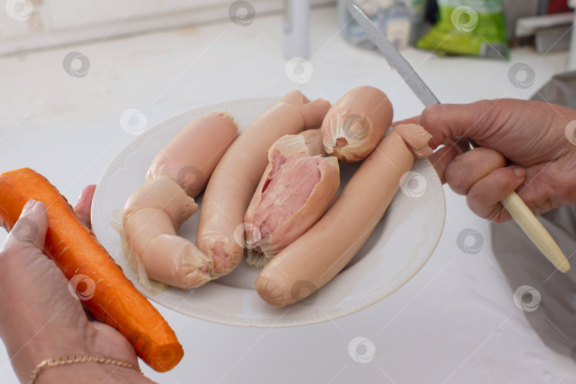 Скачать Руки держат тарелку с едой и вареными сосисками. фотосток Ozero