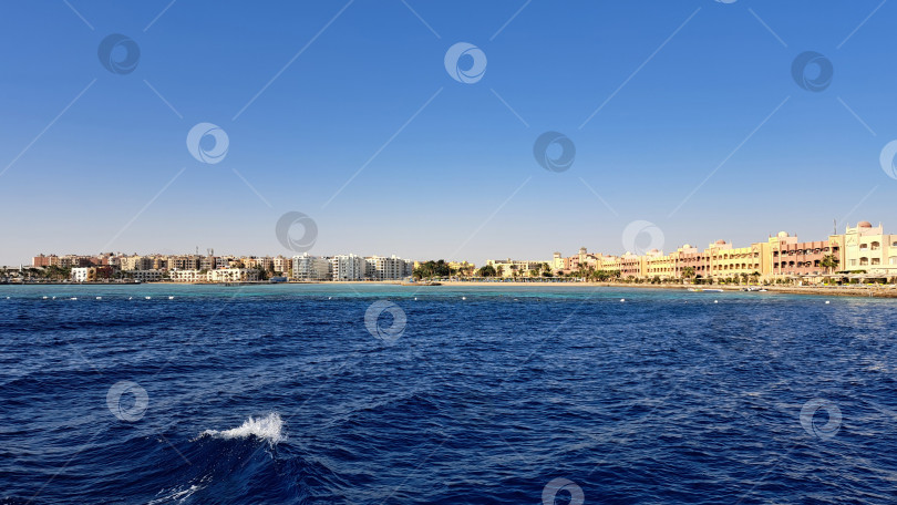 Скачать Живописный вид на побережье со спокойными голубыми водами и яркими зданиями вдоль береговой линии, передающий суть безмятежной пляжной атмосферы. Красное море. Хургада. Египет фотосток Ozero