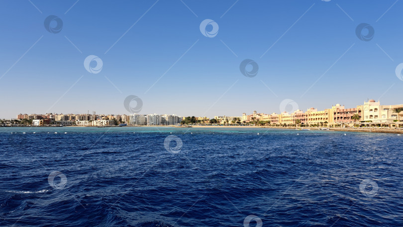 Скачать Живописный вид на побережье с яркими зданиями вдоль береговой линии, спокойные голубые воды и чистое небо создают безмятежную атмосферу для отдыха и наслаждения. Красное море. Хургада. Египет фотосток Ozero