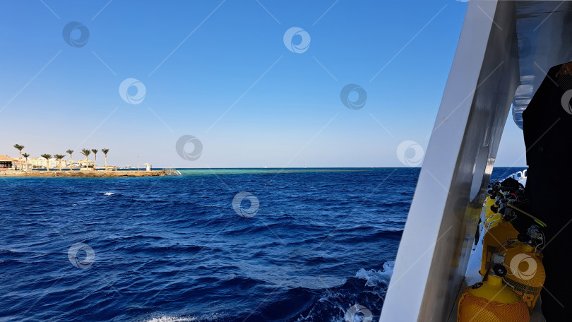 Скачать Живописный вид на темно-синие океанские волны с отдаленной береговой линией и пальмами под ясным голубым небом, создающий безмятежную атмосферу побережья и спокойствия. Красное море. Хургада. Египет фотосток Ozero